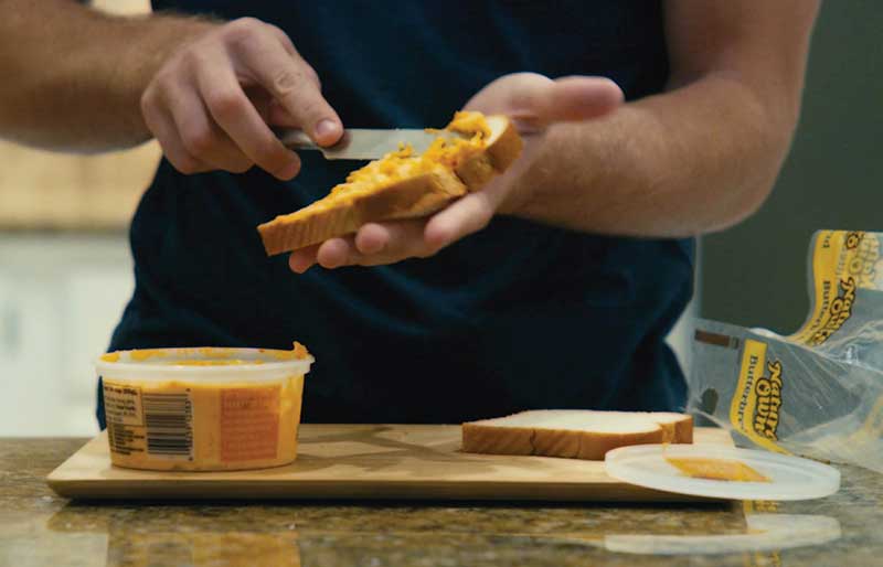 man spreading pimento cheese on bread